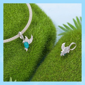 Macro d'une breloque oiseau en argent 925 avec pierre turquoise sur fond de mousse