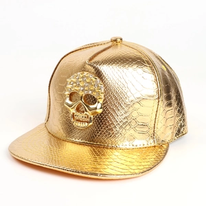Close-up of golden faux snake skin texture and metallic skull ornament on hip hop hat