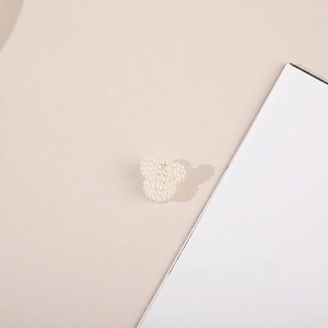 Detailed view of pearl Mickey-shaped hair clip with smooth luster on elegant background
