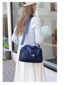 Detail view of dark blue nylon crossbody bag with adjustable strap and handles on model