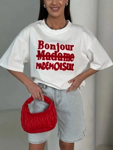 Detail of red quilted texture handbag paired with a white cotton graphic t-shirt