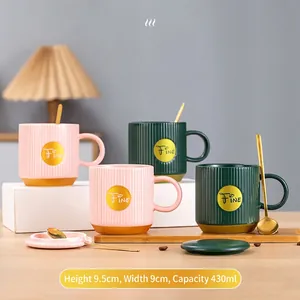 Nordic ceramic mugs in pink and green with gold bases, matching lids, and gold spoons