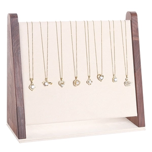 Walnut wood necklace display stand with beige velvet lining and gold pendant jewelry