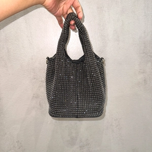 Detail view of a black rhinestone bucket bag with a chain strap for elegant evening events