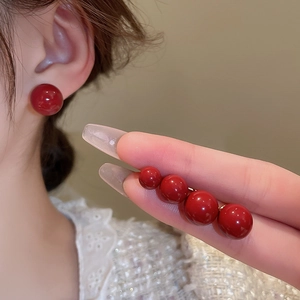 Detail showing four sizes of polished red bead stud earrings displayed on ears