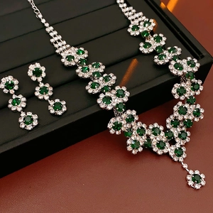 Detailed view of silver flower necklace and earrings set with green gemstones