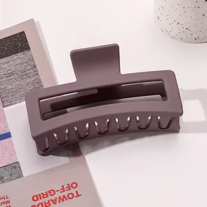 Macro detail of large matte purple hollow hair claw clip on white table