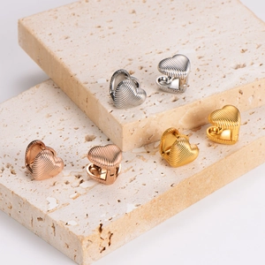 Striped heart hoop earrings in gold, silver and rose gold on a stone display stand