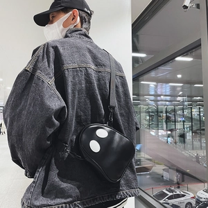Detail of black crossbody bag featuring funny white eye patches and nylon shoulder strap