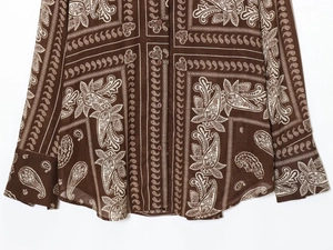 Detail of dark brown paisley print shirt showing fabric texture and resin buttons