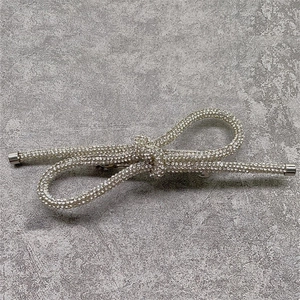 Detail of a knotted bow hair clip featuring sparkling rhinestones and metal end caps