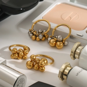 Set di anelli e orecchini con sfere in oro e argento lucido su sfondo lifestyle