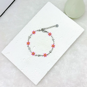 Close-up of pink daisy and silver star charms on an 18k gold-plated stainless steel bracelet