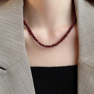 Close-up of deep burgundy red irregular stone beaded necklace worn by a fashion model