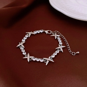 Detailed macro view of silver-toned bracelet with round zircon stones and X links