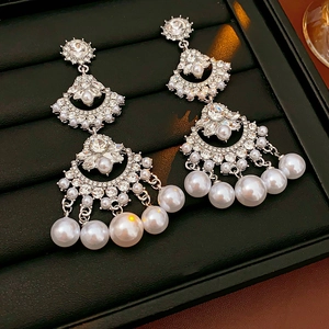 Macro view of silver chandelier earrings with pearls and rhinestones in a velvet box