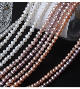 Macro shot of 5mm natural freshwater pearls in white, pink, and purple on dark background