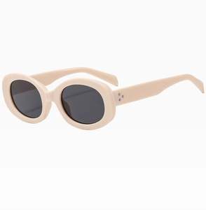 Detail shot of retro oval beige frames with dark grey lenses and triple metal rivet accents