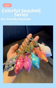 Detail of colorful seashell keychains with golden clasps and bells held in hand