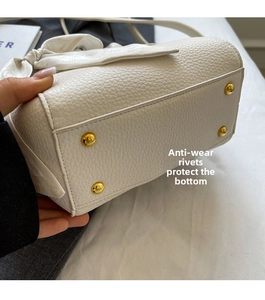 Detail of white litchi leather bag base with four protective gold anti-wear rivets