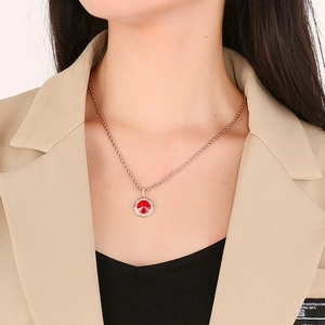 Dettaglio della collana con ciondolo in oro rosa con pietra rossa e diamanti su una modella
