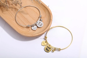 Detail van verstelbare armbanden met gegraveerde hartvormige hangers in goud- en zilverkleur