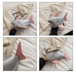 Detail view of silver shark-shaped crossbody bag with pink fins and metal chain strap