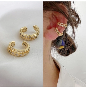 Detail view of gold double-row ear cuffs with white zircon stones on model and velvet base