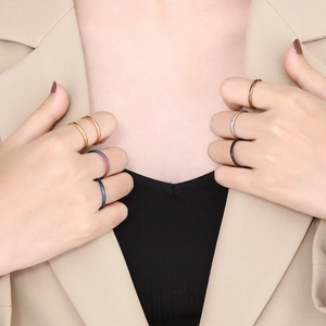 Close-up of minimalist titanium steel rings in various colors worn on female model's fingers