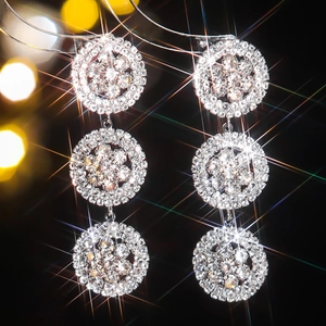 Elegant silver three-tier circular drop earrings with rhinestones on black background