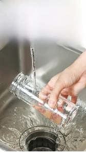 Detail of detachable glass condiment bottle being rinsed under water for easy cleaning