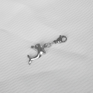 Polished stainless steel dolphin pendant with lobster clasp on white textured background
