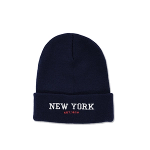 Detailed close-up of navy blue knit beanie with white NEW YORK embroidery and red EST. 1625 text