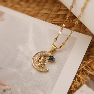Gold moon bear necklace with sparkling zircon and blue star pendant on natural background