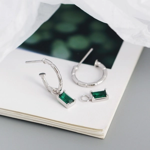 Macro detail of silver bamboo textured hoop earrings with emerald green zircon pendants