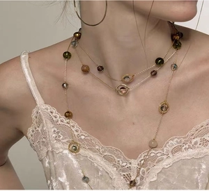 Close-up of triple-layered gold fringe necklace with amber and green crystal beads