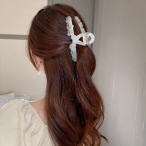 Vue détaillée d'une pince à cheveux géométrique nacrée sur des cheveux bruns ondulés