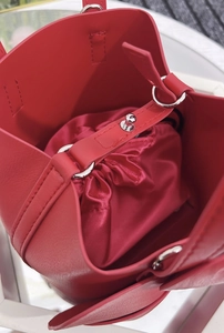 Detail of red leather bucket bag featuring a satin drawstring liner and silver metal clasp