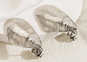 Macro detail of silver drop earrings with irregular horizontal shell-like textures