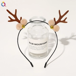 Close-up of reindeer antler headband with brown plush ears, bells and white pompoms