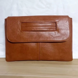 Detailed view of the brown PU leather messenger bag with top handle and fine stitching
