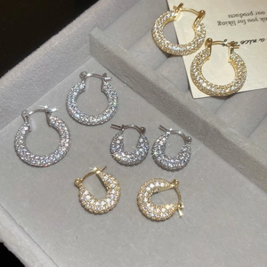 Macro shot of gold and silver U-shaped hoop earrings with zircons on a jewelry tray