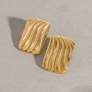 Vue détaillée de boucles d'oreilles géométriques en acier doré avec texture ondulée 3D