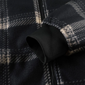 Close-up of black and white plaid fleece jacket showing ribbed cuffs and zipper detail