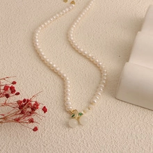 Detail shot of a baroque freshwater pearl necklace with a gold cherry-shaped pendant