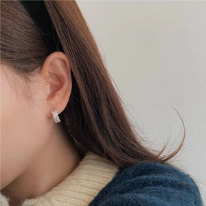 Close-up of a silver 925 sterling silver hoop earring with zircon on a model's ear