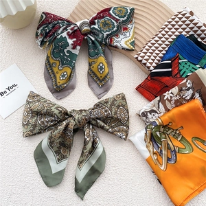 Fashionable square silk scarf with paisley and floral patterns on elegant wooden board