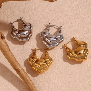Detail of 18K gold and silver double layered lotus hoop earrings on beige textured background