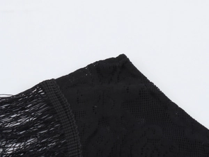 Detail shot of black lace fabric featuring intricate crochet patterns and fringe tassels