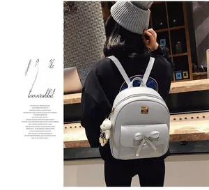 Close-up of bow decor and bear pendant on a light grey PU leather student backpack